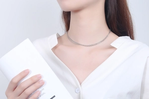Close-up of minimalist S925 sterling silver layered necklace worn on a white shirt
