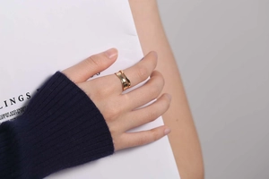 Macro detail of golden double-layer wavy ring with polished finish on a finger