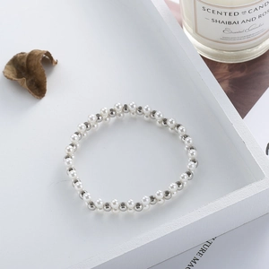 Detail of multi-layered hand-woven bracelet with white pearls and silver beads in a tray