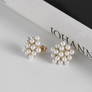 Detailed view of elegant pearl cluster earrings with gold finish on a white background