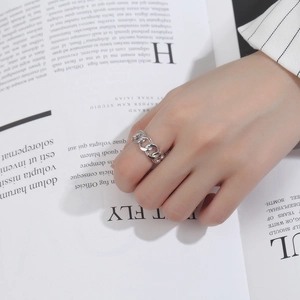 Close-up of minimalist S925 silver chain link ring worn on hand over a fashion magazine