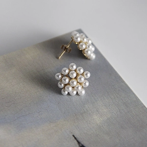 Macro shot of 925 silver pearl cluster earrings on a textured stone display board
