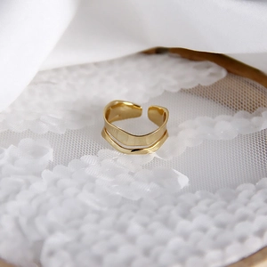 Macro view of gold wave curved layered ring displayed on white lace and silk fabric