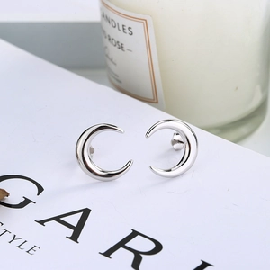 Macro shot of minimalist silver crescent moon studs on a stylish white display card