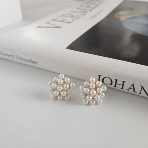 Close-up of elegant pearl flower stud earrings placed on an artistic book background