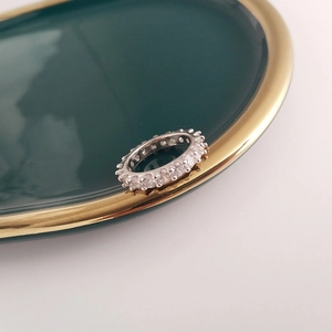 Close-up of S925 silver gear eternity ring with cubic zirconia on green ceramic