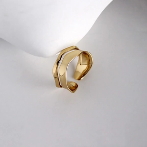 Detail of minimalist wavy gold-plated double-layer ring on a modern display