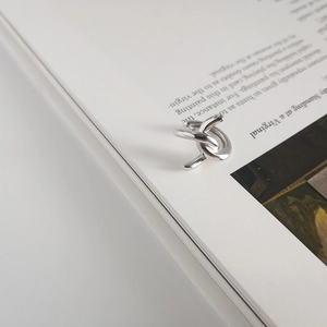Detailed close-up of a S925 sterling silver minimalist knot cuff earring on a magazine