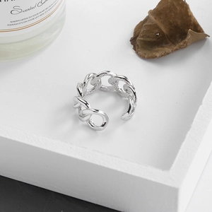 Macro shot of silver Cuban chain ring with hollow links on a white wooden tray