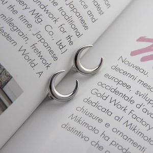 Macro view of polished S925 sterling silver crescent moon earrings on a magazine