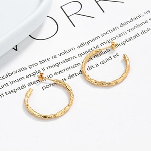 Detailed view of gold C-shaped earrings with irregular lava texture and post-back design