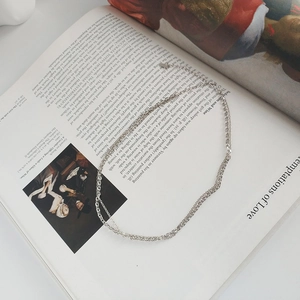 Detail of layered S925 sterling silver chain necklace on vintage art book background