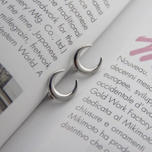Detailed view of polished S925 sterling silver crescent moon earrings on a magazine