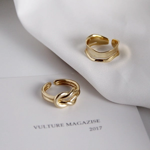 Detail of gold minimalist twist and wavy wide band rings with polished mirror finish