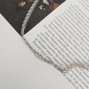 Artistic detail of a double-layered S925 sterling silver chain necklace on a book