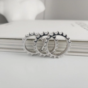 Three silver eternity rings with cubic zirconia stacked against a white book
