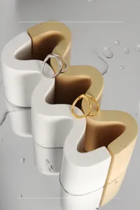 Makroaufnahme minimalistischer gewellter Ringe in Gold und Silber auf Display-Basis