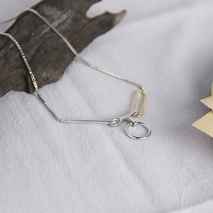 Détail d'un pendentif géométrique minimaliste avec chaîne vénitienne argentée sur tissu
