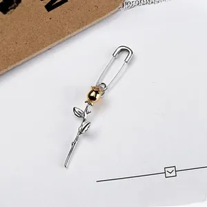 Detail of silver safety pin brooch featuring a gold-plated rose flower pendant