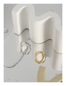 Makroaufnahme unregelmäßiger hohler geometrischer Ringe in Silber und Gold auf Spiegel