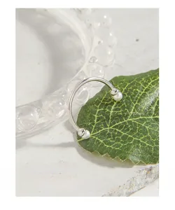 Macro shot of silver pearl open ring on green leaf with elegant water drop background