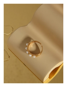 Macro detail of gold open ring featuring five white pearls on a matte geometric base