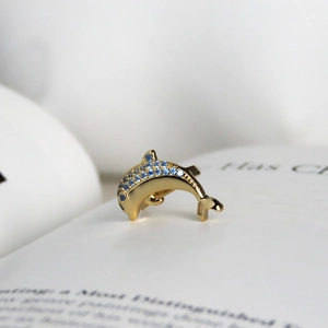 Macro shot of gold dolphin brooch with blue crystals on a minimalist background