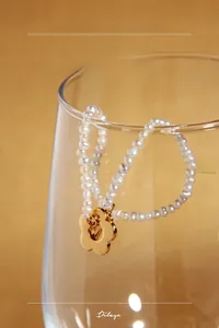 Vue détaillée du bracelet en perles d'eau douce naturelles avec un pendentif fleur dorée