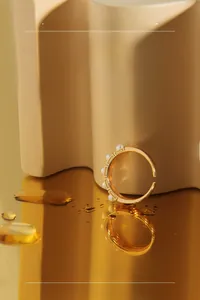 Macro shot of an adjustable gold ring with small white pearls on a reflective gold surface