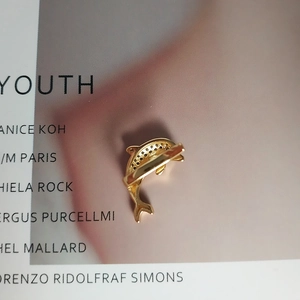 Detail of dolphin-shaped golden ear cuff with pave-set black crystals and metal texture