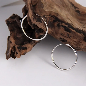 Créoles minimalistes en argent sterling S925 présentées sur un bloc de bois naturel