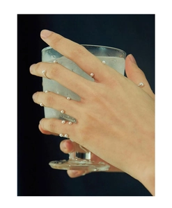 Detailed view of minimalist silver smile ring with mini pearls on model hand