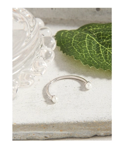 Detailed view of a silver horseshoe ring featuring elegant white pearls on a stone surface