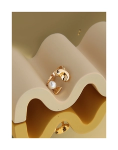 Gros plan d'une bague perle en argent S925 avec pétales dorés sur un support ondulé élégant