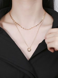 Detail of layered gold double chain necklace with round pendant on female model