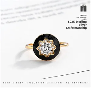 Detail of S925 sterling silver ring featuring a black disc with a golden flower and zircons