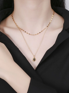 Close-up of double-layered gold S925 necklace with a black oval gemstone pendant