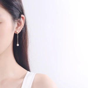 Elegant S925 silver pearl drop earrings with gold chain and crystals worn by a model