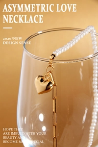 Close-up of gold heart pendant necklace featuring pearl and chain asymmetric design