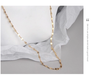 Close-up of golden S925 sterling silver flat link chain necklace on a white model