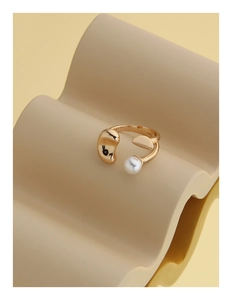 Détail d'une bague dorée ajustable au design organique ornée d'une perle blanche unique