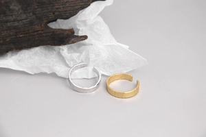 Détails de la texture martelée sur bagues ouvertes or et argent au fini irrégulier