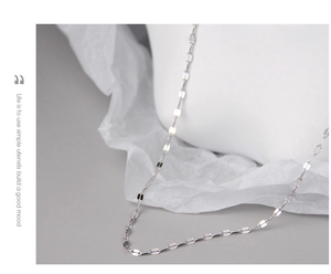 Detail of minimalist S925 sterling silver tile chain necklace with shiny metallic finish