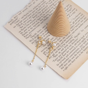 Close-up of S925 sterling silver dangling pearl earrings with elegant long gold chains