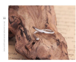 Minimalist S925 sterling silver open line ring displayed on a natural wooden block