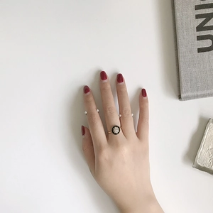 Close-up of gold plated ring set with black oval element and faux pearls on fingers