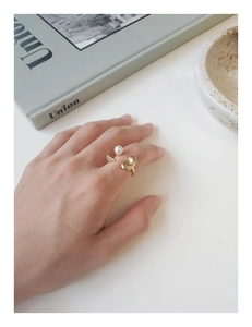 Vue détaillée d'une bague dorée élégante avec perle et lignes fluides sur le doigt