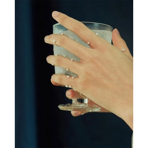 Minimalist 925 sterling silver ultra-thin rings with delicate pearls on hand holding a glass