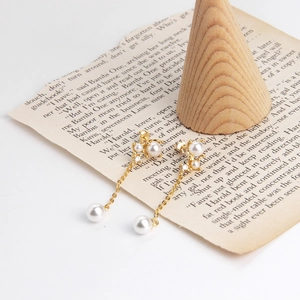 Detail of gold pearl drop earrings with crystal accents on a vintage book background