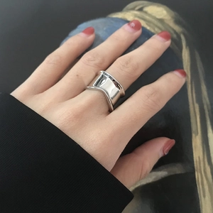 Macro detail of a wide concave S925 silver ring with a polished mirror finish on a finger